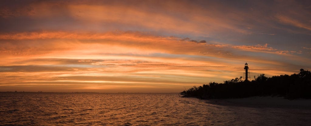 A red sunrise over ocean and lighthouse as I think about questions about cancer