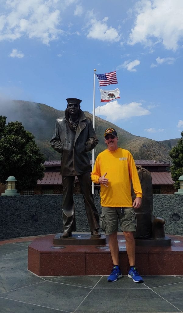 Dan Dry Dock Shockley, a colon cancer survivor and Navy veteran stands in front of a memorial. 