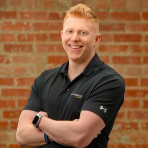 A healthy looking Matt Ode, a testicular cancer survivor, smiles in a black shirt